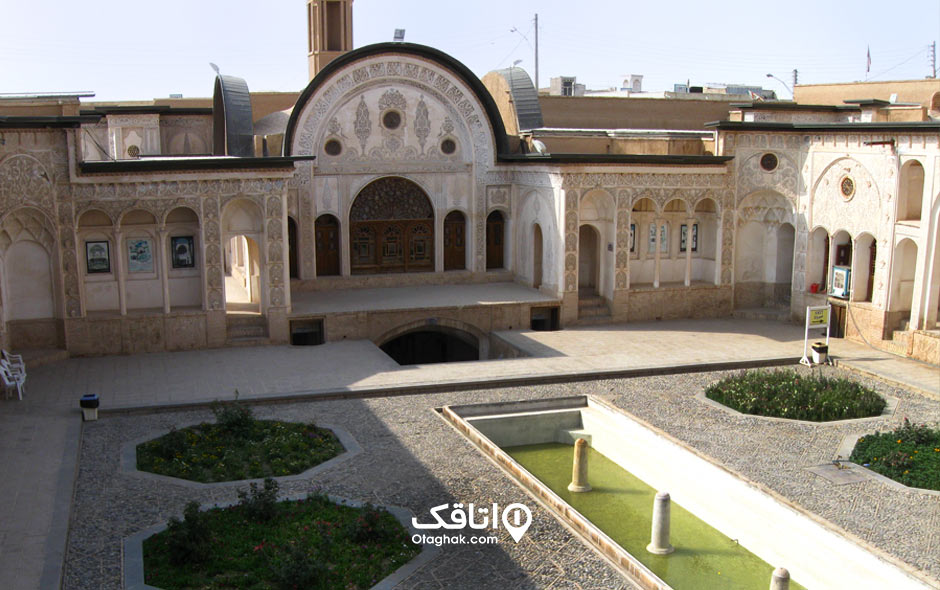خانه ای بزرگ با نمایی سفید که روی آن گچ کاری های ظریف انجام شده، حوضی کشیده در میان حیاط با چند فواره به نامخانه طباطباییها کاشان