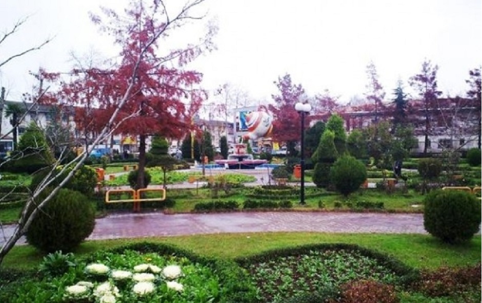 پارکی با چمن و درختان و شمشماد های شکل گرفته شده در یک روز بارانی
