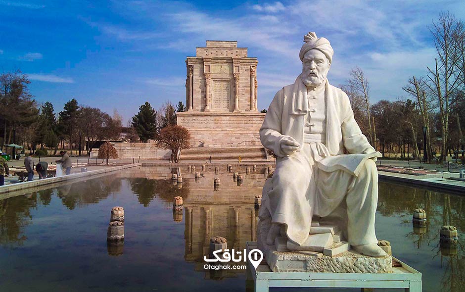 مجسمه مردی به نام فردوسی رو به روی حوضی بزرگ و پست آن ساختمان آرامگاه فردوسی 