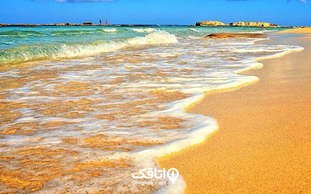 شن های زیبا و کرم رنگ ساحل خلیج فارس ، کف به وجود آمده توسط امواج و آسمانی آبی