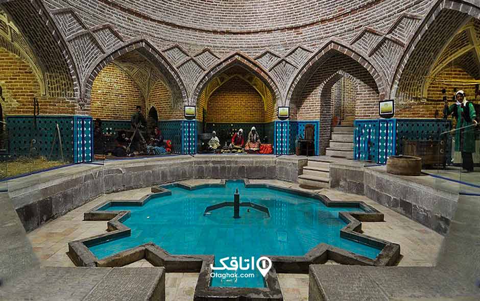 حمامی قدیمی با دیوار های آجری و پایین دیوار ها کاشی کاری آبی شده و یک حوض در وسط