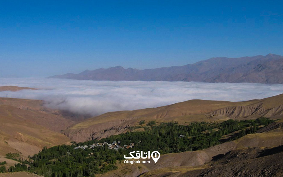 جنگل ابر بالای یک کوهستان که درون کوهها جنگل و خانه های مسکونی قرار گرفته