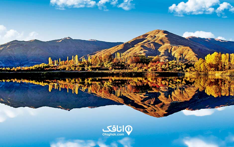 دریاچه که عکس کوهی بلند و درختان رنگانگ در آن انعکاس پیدا کرده است به نلم دریاچه اوان قزوین