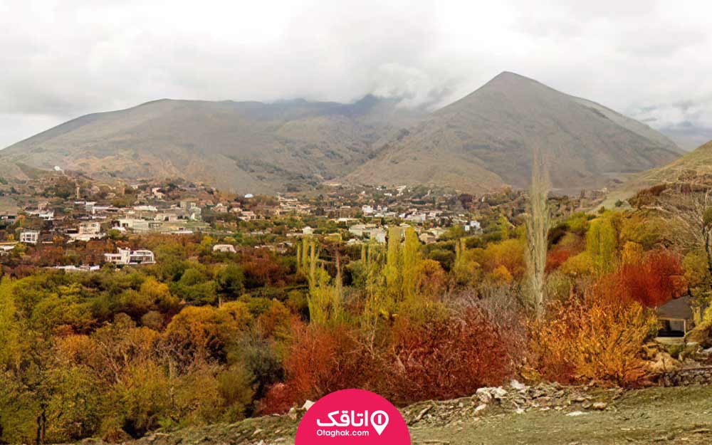 نمایی از یک روز پاییزی یک روستا با درختان رنگارنگ و کوه هایی که قله آن ها را مه گرفته است