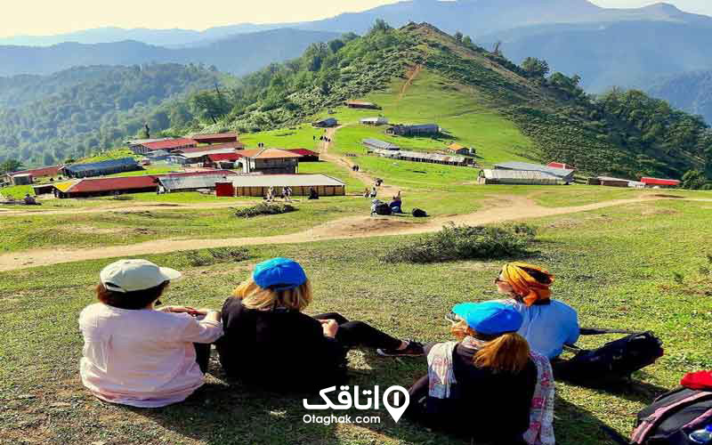 ۴ خانوم روی یک تپه نشسته و تماشاگر منظره ی خانه های روی تپه ی مقابل و جنگل پشت سر آنها هستند