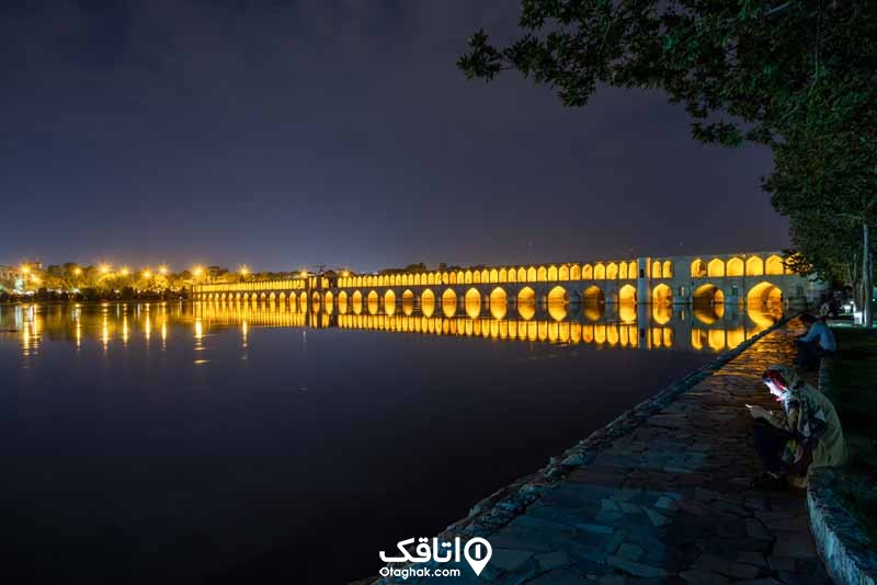 پلی قدیمی دالان دالان به نام 33 پل در شب که انعکاس ان در آب روخانه زاینده رود مشخص است