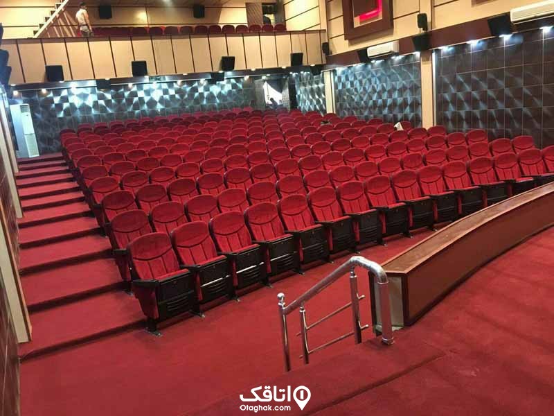 یک سالن سینما با صندلی های قرمز رنگ و کف موکت قرمز
