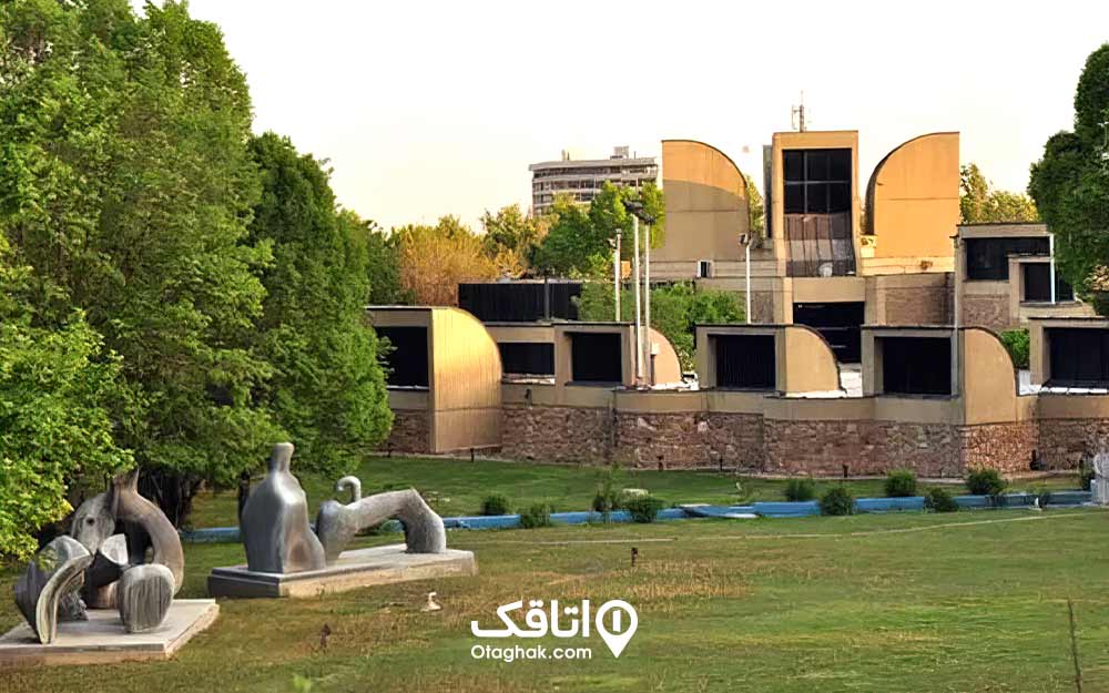 ساختمانی با معماری عجیب در میان محطه چمن کاری شده و مجسمه هایی خلاقانه در محوطه به نام موزه هنر های معاصر ایران