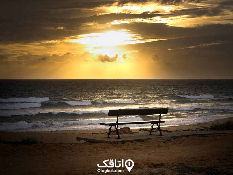 تصویر یک صندلی لب دریا در غروب آفتاب در شهر بابلسر، که موج های دریا به سمت صندلی حرکت میکنند