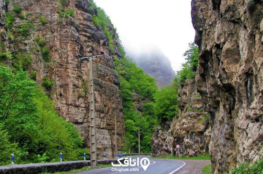 جاده ای در دل کوهستان که دو طرف آن کوه های صخره ای و درختان سر سبز است