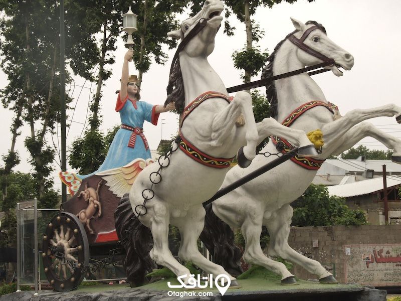 مجسمه دو عدد اسب که به یک درشکه بستهشده است و خانمی در حال هدایت آنها