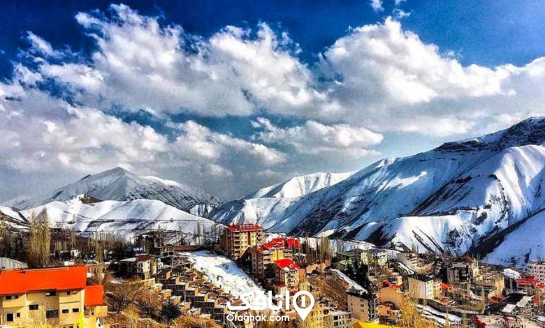 نمایی از یک روستا در فصل زمستان در حالیکه روی کوه ها پوشیده از برف است 