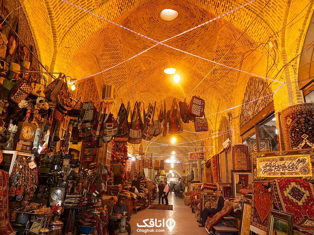 یک بازار دالانی سنتی و مغازه هایی که اجناسی مانند فرش، تابلو،کیف هایی را جلوی درب هایشان چیده اند