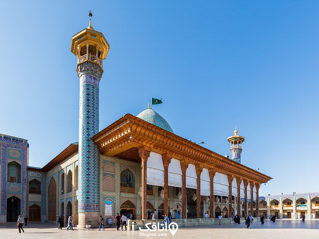 نمایی از صحن ورودی، گنبد آبی رنگ و دو گل دسته و ستون های چوبی مسجد شاهچراغ