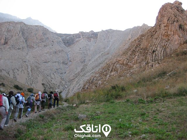 تعدادی کوهنورد در حال عبور از دشت بین کوهستان