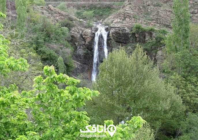 آبشاری در کوهستان و درختان سبز رنگ در اطراف ان