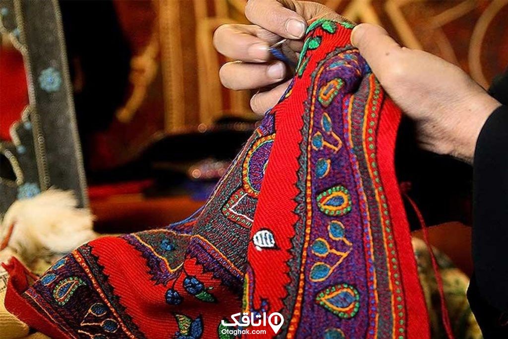 دستان یک خانم در حال رودوزی سنتی روی یک پارچه 