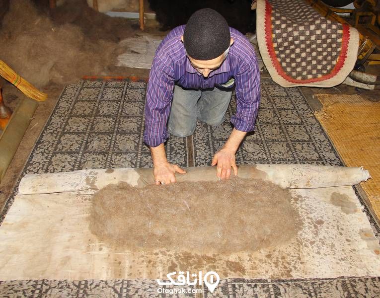 مردی در حال لوله کردن پارچه نمدی
