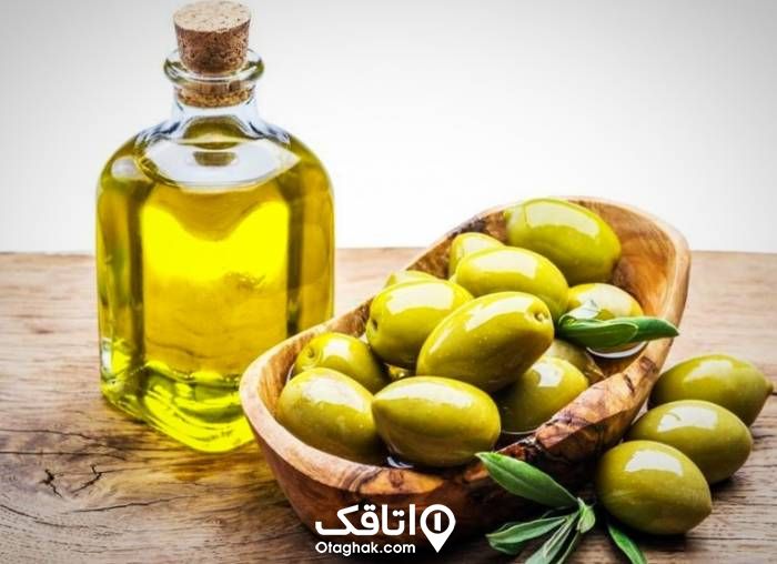 ظرف چوبی پر از زیتون در کنار یک ظرف شیشه ای پر از روغن زیتون