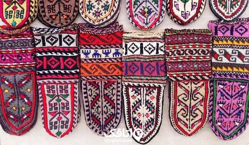 تعدادی جوراب پشمی در طرح ها و رنگ های متنوع که به دیوار آویزان شده اند
