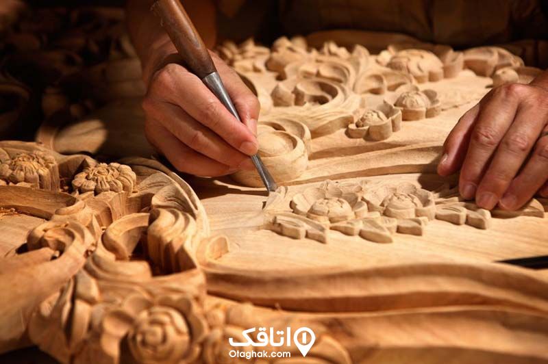 دستان یک نفر در حال انجام هنر منبت بر روی چوب