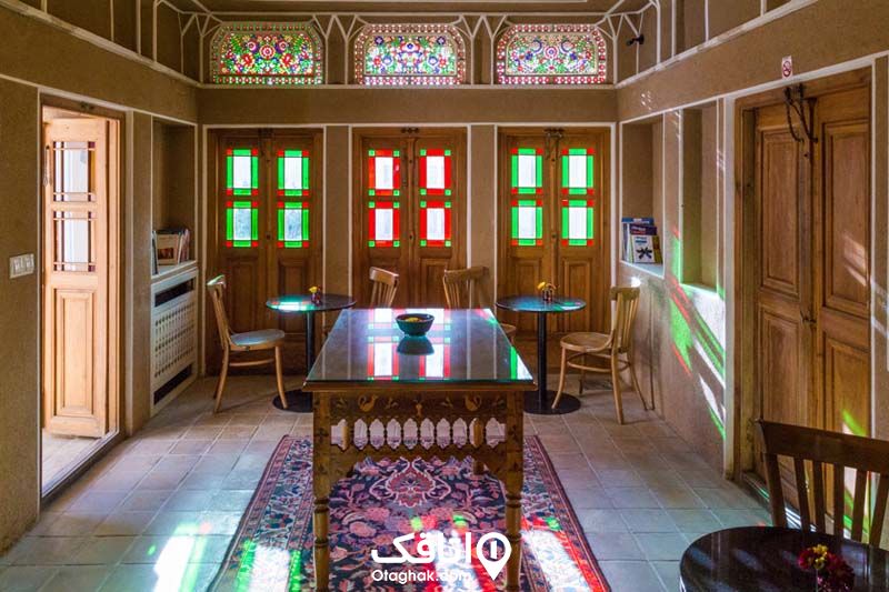 داخل رستورانی سنتی در کاشان با در و پنجره های چوبی بلند و شیشه های رنگی و میز و صندلی ظریف چوبی