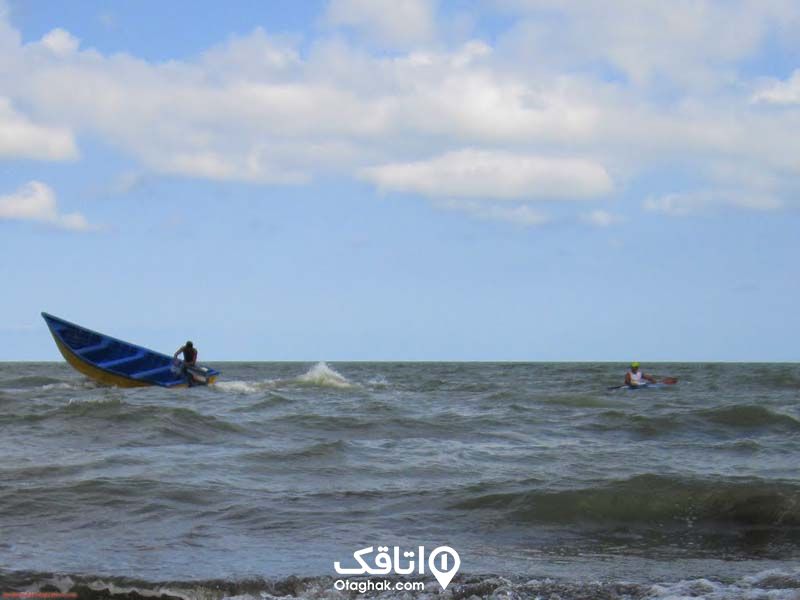یک مرد سوار بر قایق موتوری و مردی داخل آب دریا