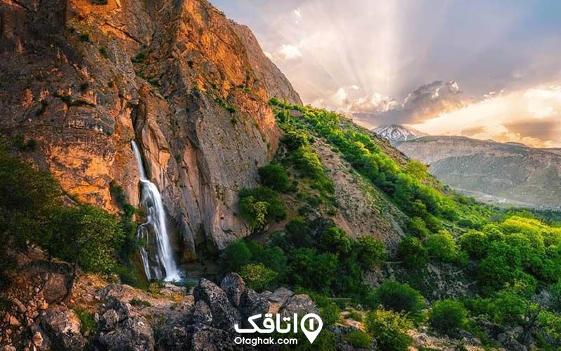 منظره ای زیبا از سرازیر شدن یک آبشار در کوهستان و طبیعت اطراف آن 