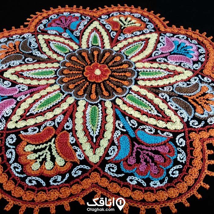 یک گل زیبا و رنگی که با سوزن دوزی روی یک پارچه مشکی انجام شده.