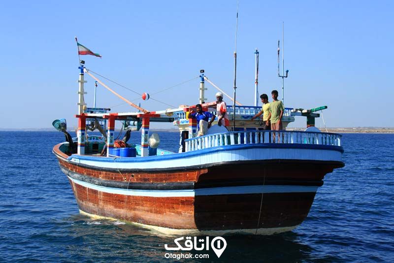 یک لنج روی دریای آبی رنگ خلیج فارس و تعدادی آدم داخل لنج روی عرشه