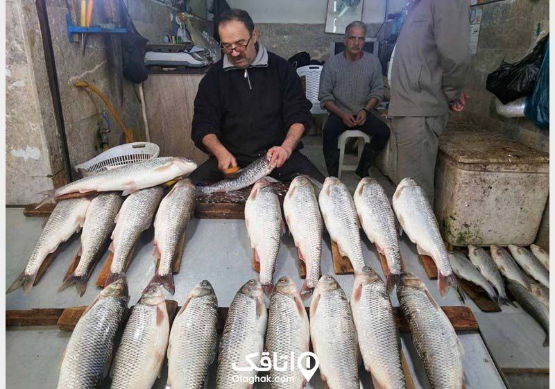 مردی در حال پاک کردن ماهی در ماهی فروشی 