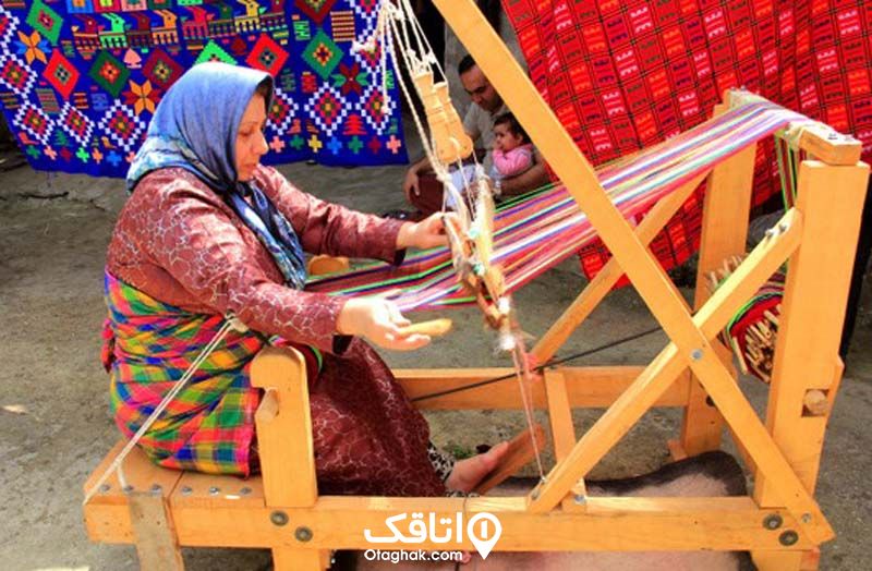زنی در حال بافتن گلیم با ابزاری چوبی 