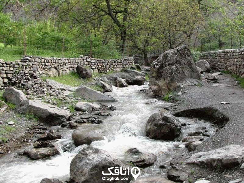 رودخانه کرگان رود در حال عبور بین دو باغ و سنگ های بزرگی که سر راهش قرار دارند.