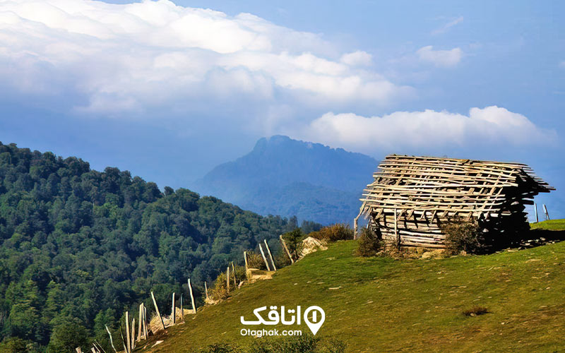 منظره ی کوه های پوشیده از درخت . یک کلبه چوبی روی تپه سرسبز در روستای مازیچال