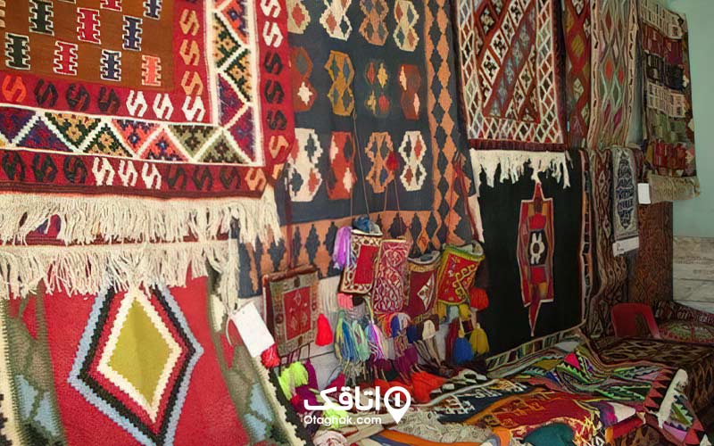 تعدادی فرش و گلیم دست باف در مغازه‌ای در شمال ایران