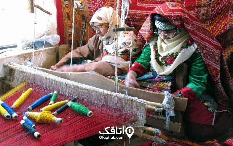 دو زن پشت دستگاه پارچه بافی و مشغول بافت پارچه هایی سوغات شمال ایران