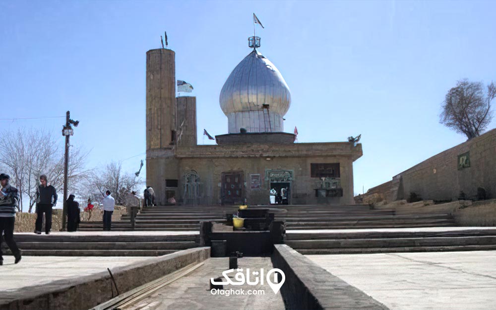 چند نفر در حال قدم زدن محوطه امام زاده شاه عبدالقاسم با گنبد نقره ای رنگ و دو گل دسته