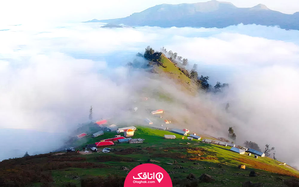 یک کوه بلنر که روی آن ملبه هایی با سقف های رنگی ساخته شده و مه قسمتی از کوه را فرا گرفته