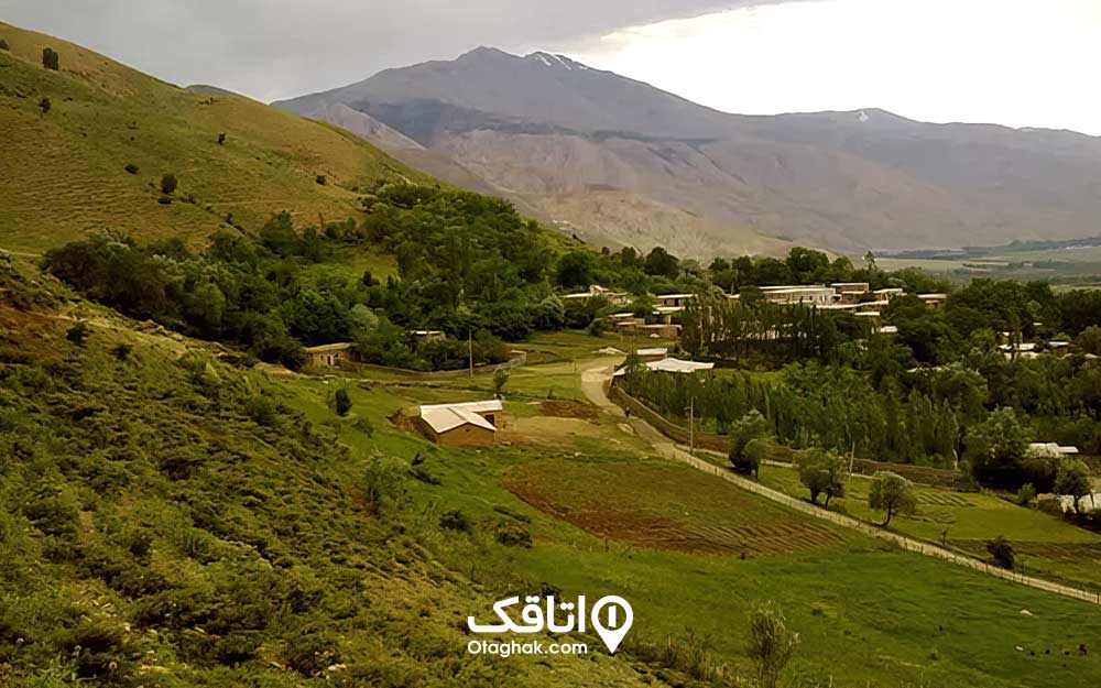 نمایی دور از یک روستا درختان، کوه ها و سرسبزی آن 