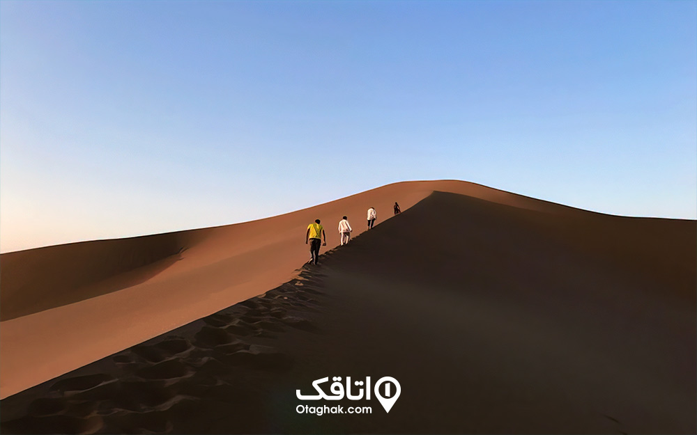 چند نفر در حال قدم زدن روی تپه های شنی کویر مصر از جاهای دیدنی خور و بیابانک 