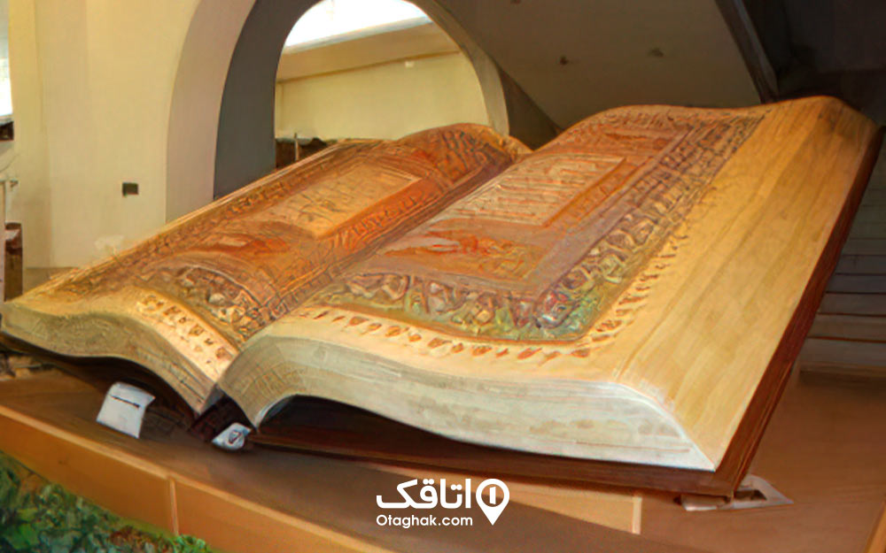 یک کتاب قران بزرگ که باز شده است و صفحات داخلی آن دارای نقش های رنگی هستند.