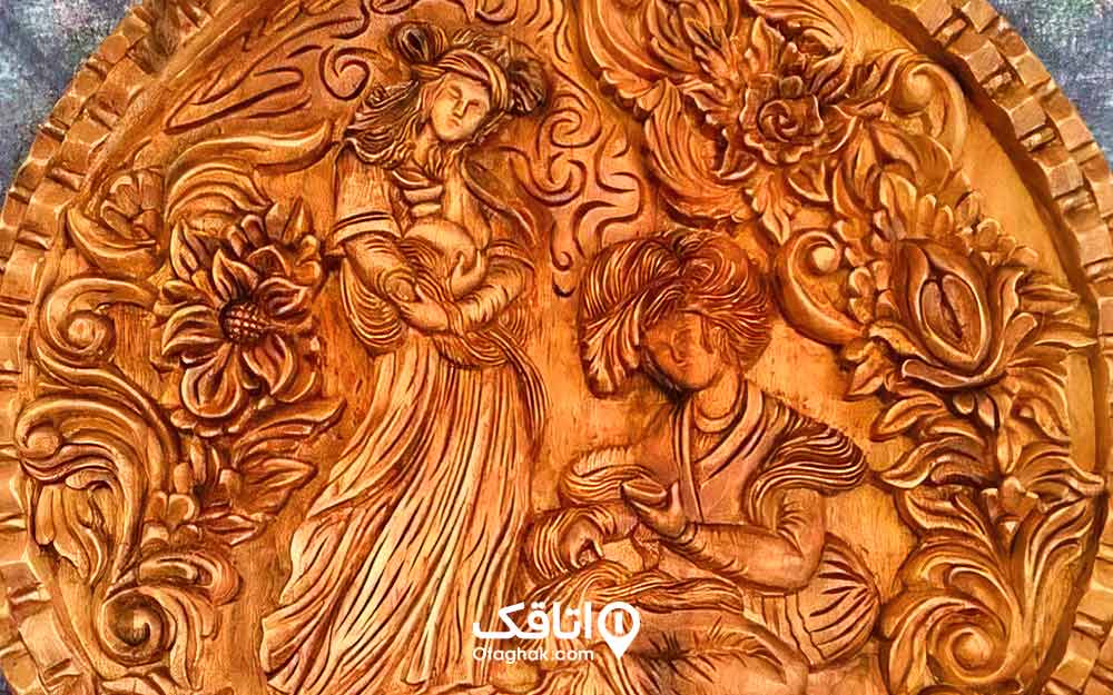 طرح یک زن و مرد و تعدادی گل و نقش اسلیمی بر روی چوب به وسیله هنر منبت کاری.