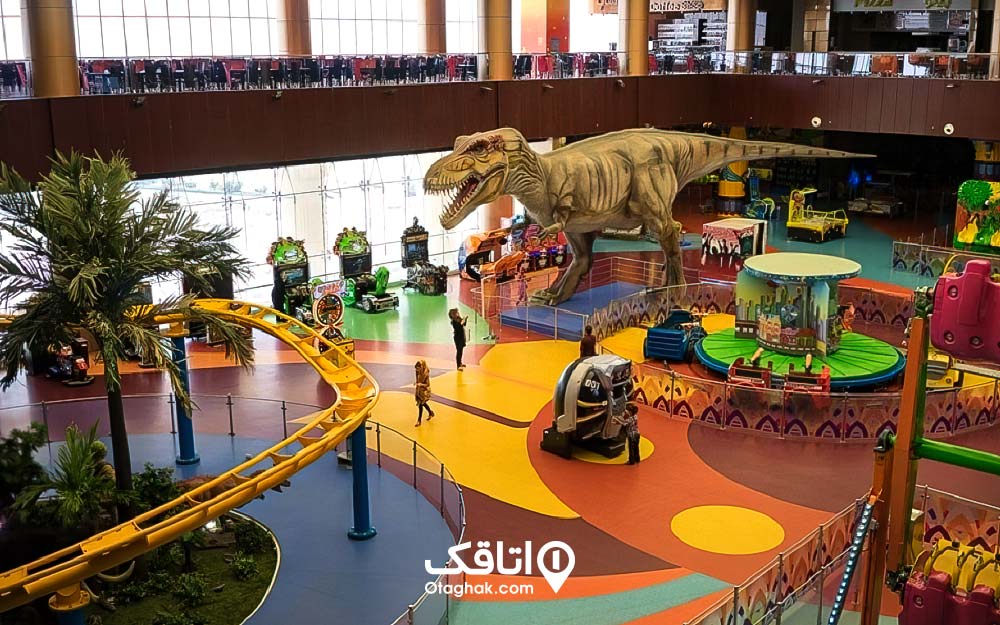 محوطه ای برای بازی کودکان و بک مجسمه دایناسور در وسط آن