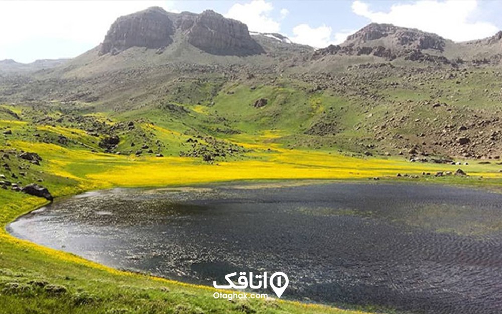 دریاچه در ذز یک دشت با گل هاب زرد و پایین یک کوه