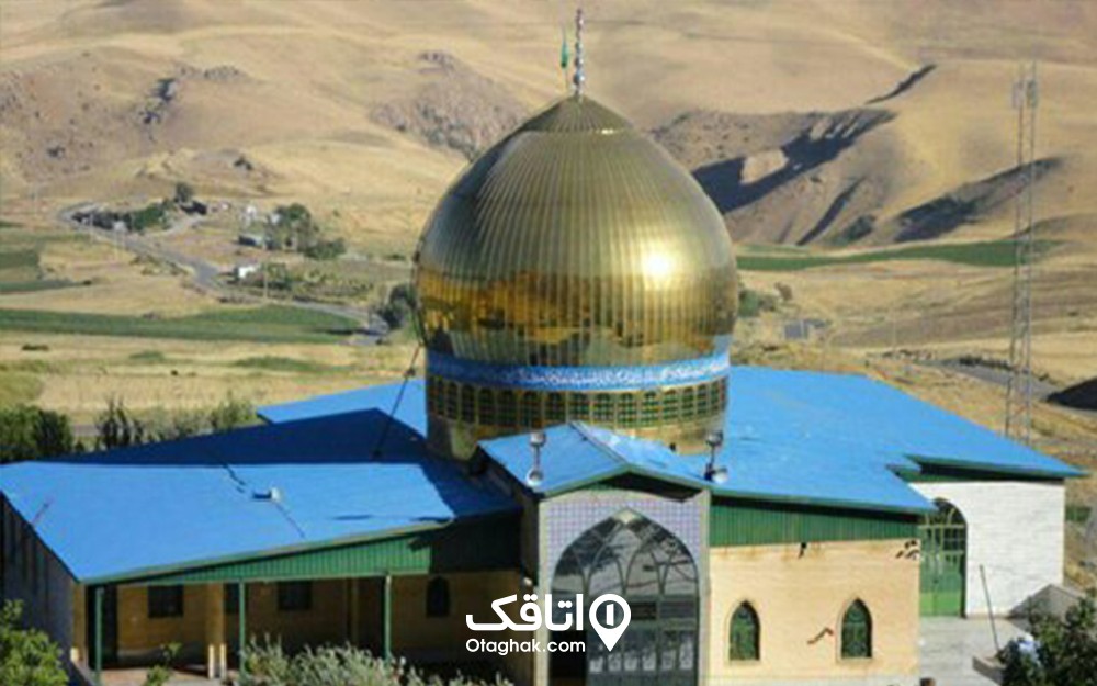 ساختمان یک طبقه ای با سقف شیروانی آبی رنگ و کنبدی طلایی به نام امامزاده سید محمد مکه دین