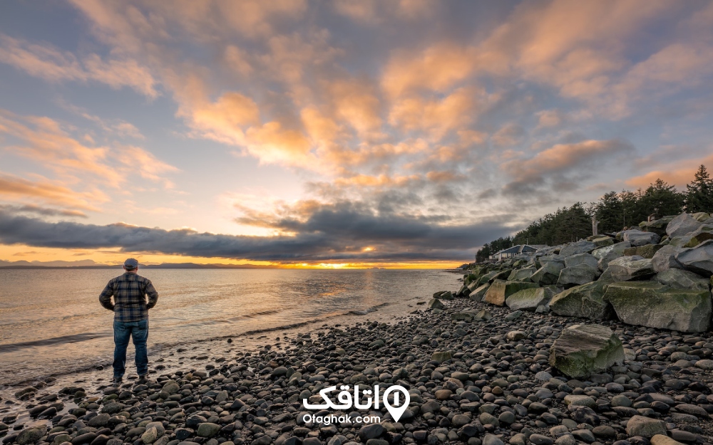 نمایی از مردی که رد ساعت طلایی عکاسی رو به ساحل ایستاده